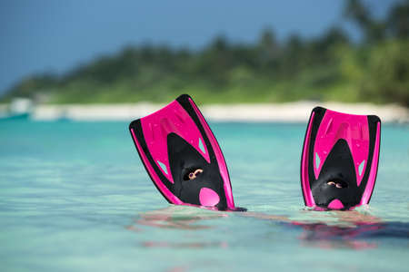 Woman relaxing on summer beach vacation holidays lying in sand. Flippers in legs. Diver finsの写真素材