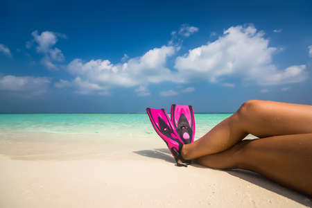 Woman relaxing on summer beach vacation holidays lying in sand. Flippers in legs. Diver finsの写真素材