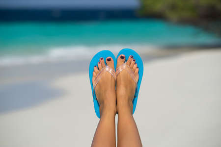 Close-up of female foot in the blue water on the tropical beach. Vacation holidays.
