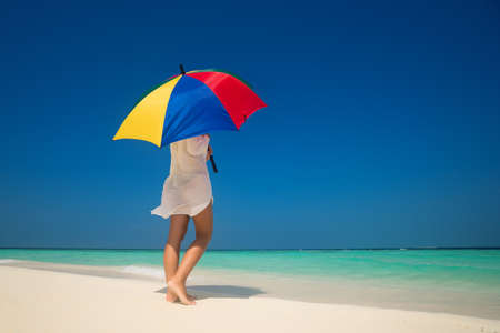 Girl with an colorful  umbrella on the sandy beachの写真素材