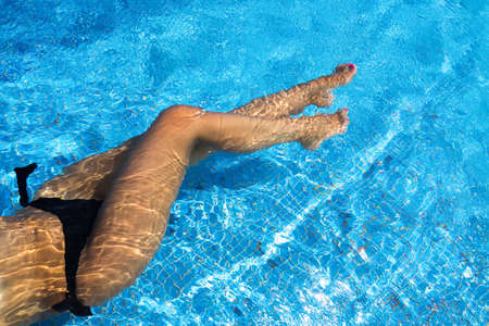 Closeup of beautiful female legs in water of a poolの写真素材