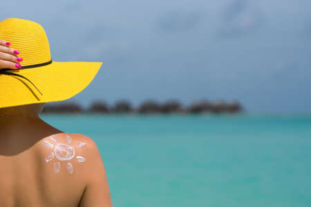Woman with sun-shaped sun cream on beach