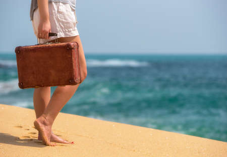 Beautiful girl with a old vintage suitcase in a beachの写真素材
