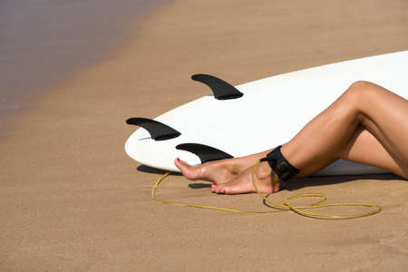 Young beautiful surfer girl on beach with surf board at day break