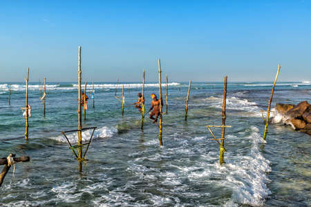 WELIGAMA, SRI LANKA - JANUARY 11 2017: Unidentified local fishermen are fishing in unique style. This type of fishing is traditional for Sri Lanka in Indian ocean.のeditorial素材