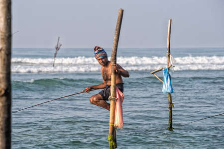 WELIGAMA, SRI LANKA - JANUARY 11 2017: Unidentified local fishermen are fishing in unique style. This type of fishing is traditional for Sri Lanka in Indian ocean.のeditorial素材