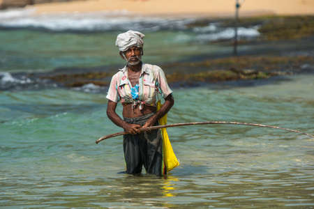 WELIGAMA, SRI LANKA -  JANUARY 18, 2017:  Portrait of local fisherman sitting on boat. Tourism and fishing are two main business in this town.のeditorial素材