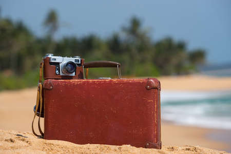 Travel  vintage suitcase and camera on a beachの写真素材