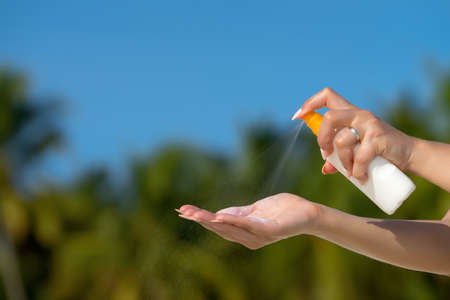 Woman hands putting sunscreen from a suncream bottle