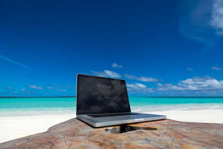 laptop blank screen on wooden desk with beach. relax concept.の写真素材