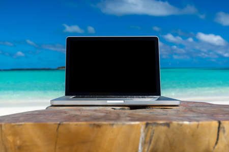 laptop blank screen on wooden desk with beach. relax concept.の写真素材