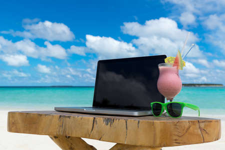 laptop blank screen on wooden desk with beach. relax concept.の写真素材