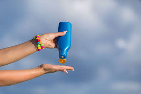 Woman hands putting sunscreen from a suncream bottleの写真素材