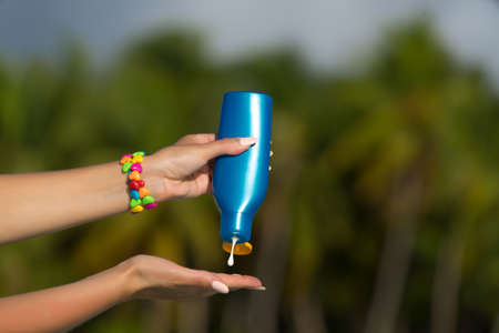Woman hands putting sunscreen from a suncream bottleの写真素材