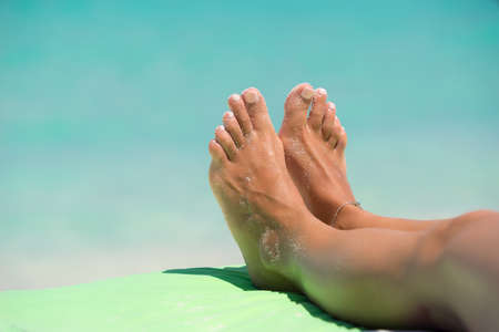 Close-up of female foot in the blue water on the tropical beach. Vacation holidays.の写真素材
