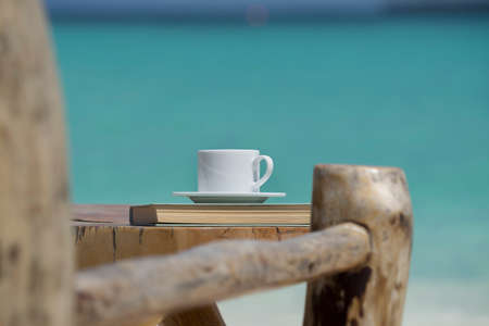 A cup of coffee in a white cup on beach sea backgroundの写真素材