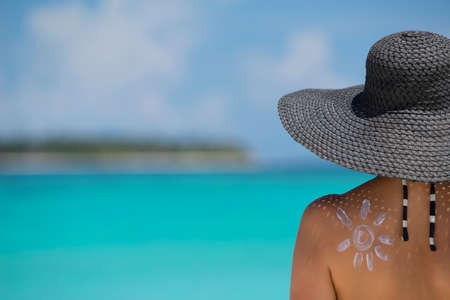 Woman with sun-shaped sun cream on beach