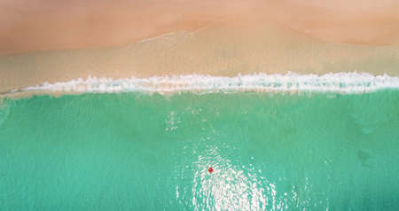 Aerial view of slim woman swimming on the swim ring  donut in the transparent turquoise sea in...