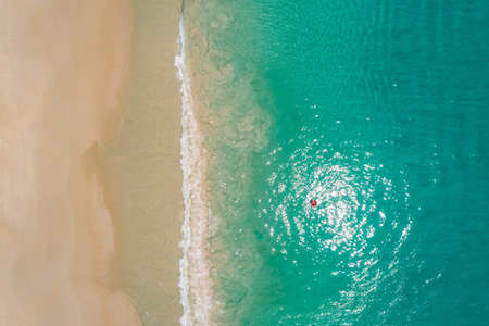 Aerial view of slim woman swimming on the swim ring  donut in the transparent turquoise sea in Seychelles. Summer seascape with girl, beautiful waves, colorful water. Top view from droneの写真素材