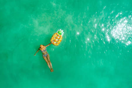Aerial view of slim woman swimming on the transparent turquoise sea. Summer seascape with girl, beautiful waves, colorful water. Top view from droneの写真素材