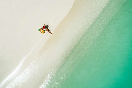 Aerial view of slim woman swimming on the transparent turquoise sea. Summer seascape with girl, beautiful waves, colorful water. Top view from droneの写真素材