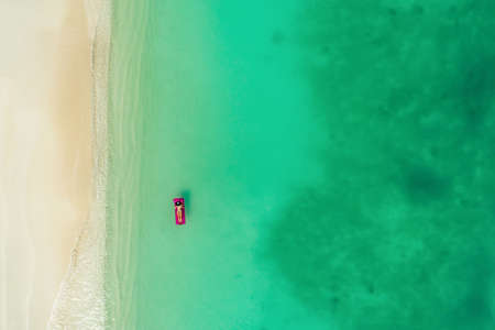 Aerial view of slim woman swimming on the swim mattress in the transparent turquoise sea. Summer...