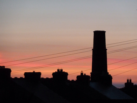 Black silhouetted skyline with chimneys and a sunset skyの写真素材