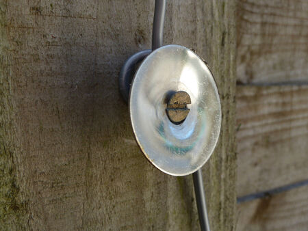 Bright shiny circular object screwed to a wooden panelの写真素材