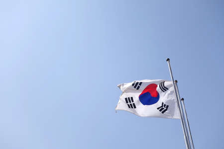 SOUTH KOREA flag floating in the wind with a blue sky in the background.の写真素材