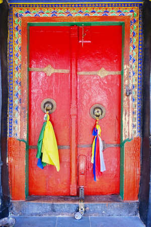 Old door at Buddhist monastery temple decorated with ancient doorknob and tassel.の写真素材