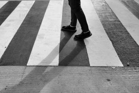 Legs of man in black jeans and crossing street, monochromeの写真素材