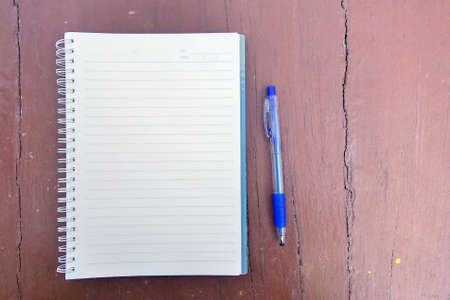 Open note book with pen on wooden background.の写真素材