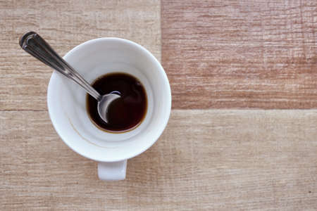 nearly empty cup of coffee with spoon in itの写真素材