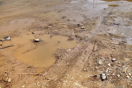 muddy ruin road with tire tracks and water after heavy rain.の写真素材