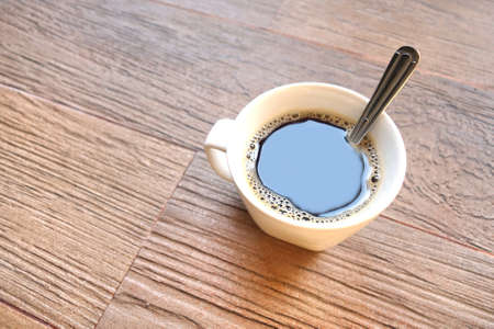 a cup of black coffee with spoon in it.