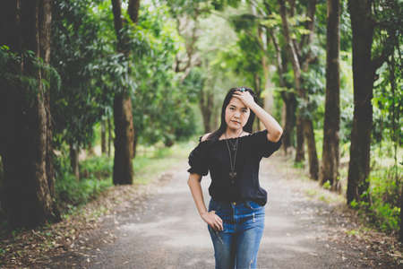 Portrait a beautiful asian woman make sleek hair at forest in the morningの写真素材
