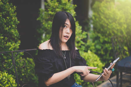 Beautiful asian woman holding and using tablets in gardenの写真素材