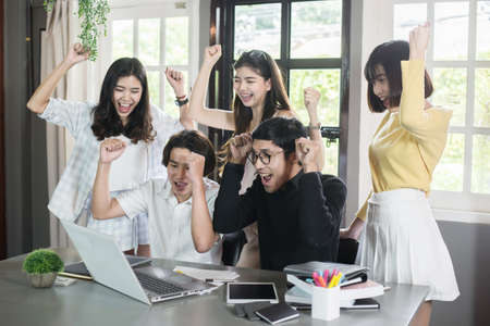 Group of successful students is celebrating working together sitting in coworking spaceの写真素材