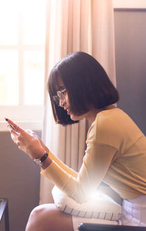 Asian young woman using smartphone at home,Searching or social networks,beautiful teenagerの写真素材