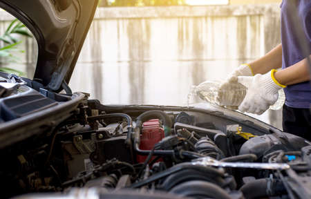 Mechanic fill fresh water into windscreen or in water tank wiper on car engine room
