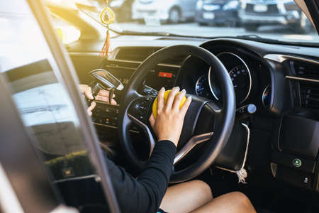 Female worker cleaning car inside dashboard with waxyの写真素材