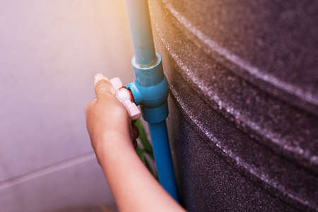 Hand using water pipes and water tank for consume
