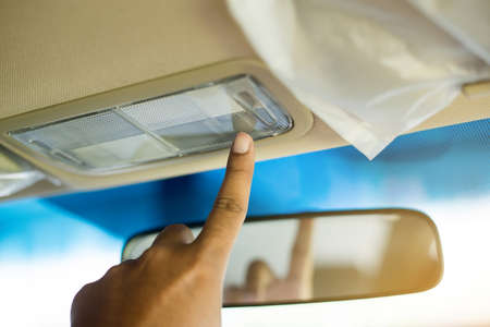 Finger pressing ceiling light in the car,Selective focus