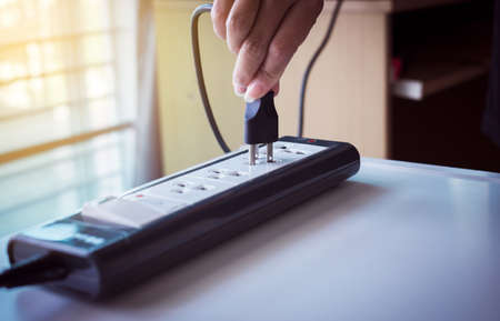 Hand with electric plug or puts plugs in the socket 