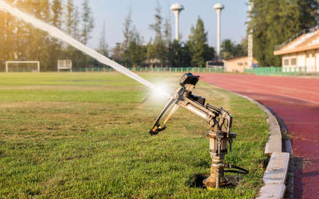 Sprinklers spraying water on grass in the football fieldの写真素材