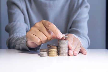 Close up of hand putting coins stacks on a table,Saving money conceptの写真素材