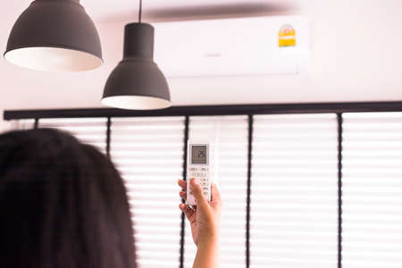 Hand using a remote control to activating air conditioning の写真素材