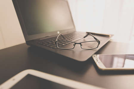 Glasses on laptop computer with pen on deskの写真素材