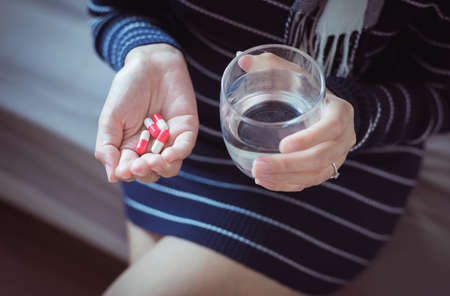 Woman sick with capsules on hand and a glass of water,Concept for healthの写真素材