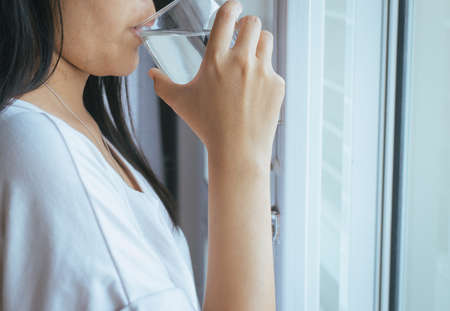 Woman drinking a glass of water after waking upの写真素材